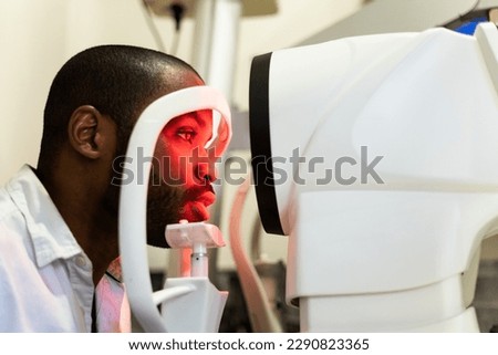A dark-skinned man is undergoing a vision test using a corneal topographer to examine the cornea. Concept of corneal topography in men. Eye care. Royalty-Free Stock Photo #2290823365