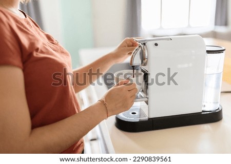 Unrecognizable Lady Using Coffee Machine In Kitchen At Home, Young Female Holding Cup And Pouring Caffeine Drink With Modern Appliance, Millennial Woman Enjoying Morning Beverage, Cropped Image