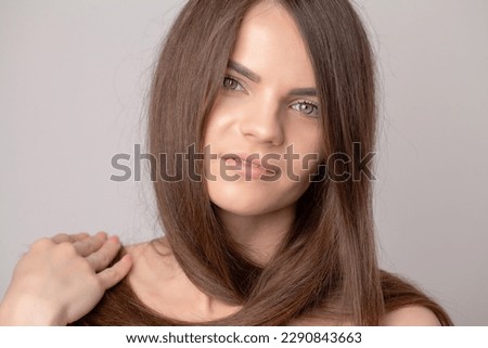 Beautiful young woman holding her healthy and shiny hair.
