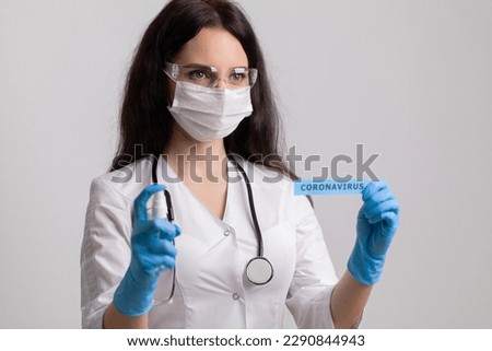 Female doctor in uniform holding a paper signboard lettering coronavirus.