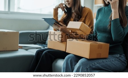 Checking clients address, Young pretty Asian female influencer small businesses SME owners female entrepreneurs working on receipt box and check online orders, sitting on sofa of home online business