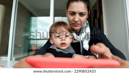 Parent and child using cellphone. Mother and toddler holding smartphone