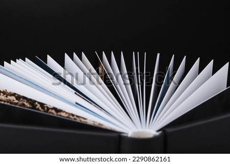 A beautiful leather bound book against a black background. Stylish book WITH OPEN PAGES on dark black background. The texture of a photobook made of genuine leather. 