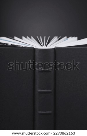 A beautiful leather bound book against a black background. Stylish book WITH OPEN PAGES on dark black background. The texture of a photobook made of genuine leather. 