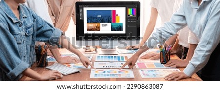 Graphic designer brainstorming logo and graphic art at busy artistic workshop, laptop display workspace. Experimenting color palette and pattern for creative design. Panorama shot. Scrutinize