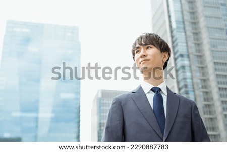 A man in a suit in his 20s and 30s looking far away with a serious expression in a business district Royalty-Free Stock Photo #2290887783