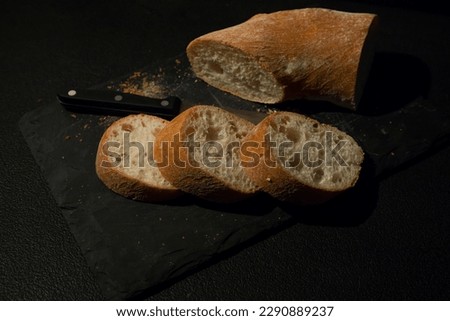 Slices of bread with crumbs and a knife on a black board background. View from above. World homemade food.