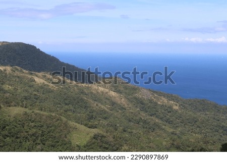 Tropical landscape. End of the earth. Aerial view of a mountain slope of a tropical island covered with jungle, sea and clouds.