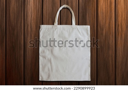 A white tote bag with a handle on a wooden background