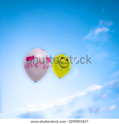 Two balloons flying in the blue cloudy sky background.Holiday, Celebration Concept.