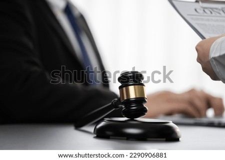 Focus shiny golden balanced scale on blurred background of lawyer colleagues working on desk at law firm office. Scale balance for righteous and equality judgment by lawmaker and attorney. Equilibrium