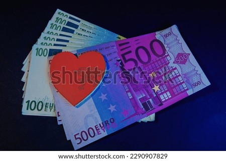 Модель человеческого сердца поверх банкнот номиналом 500 и 100 евро. Символ продажности любви.