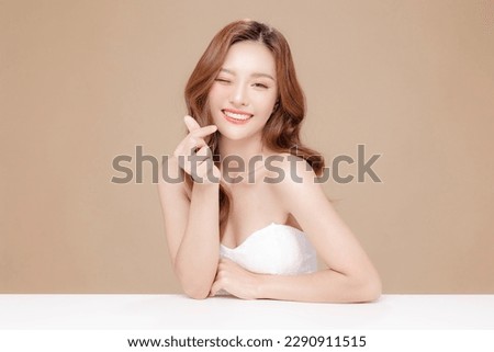 Young Asian beauty woman curly long hair with korean makeup style on face and perfect skin showing Love sign on isolated beige background. Facial treatment, Cosmetology, plastic surgery.