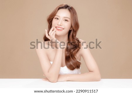 Young Asian beauty woman curly long hair with korean makeup style touch her face and perfect skin on isolated beige background. Facial treatment, Cosmetology, plastic surgery. Royalty-Free Stock Photo #2290911517