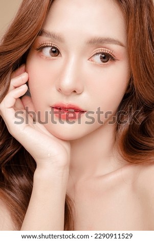Young Asian beauty woman curly long hair with korean makeup style touch her face and perfect skin on isolated beige background. Facial treatment, Cosmetology, plastic surgery. Royalty-Free Stock Photo #2290911529