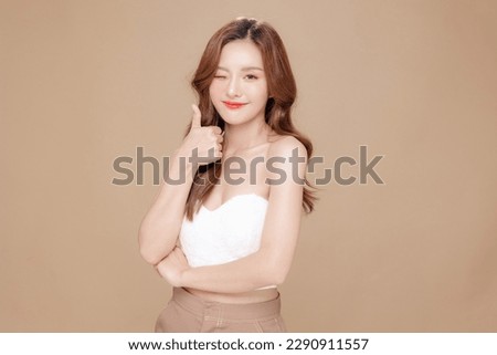 Young Asian beauty woman curly long hair with korean makeup style on face and perfect skin showing thumb up on isolated beige background. Facial treatment, Cosmetology, plastic surgery.