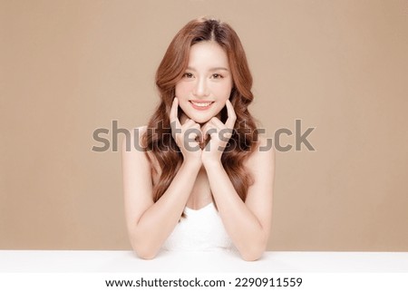Young Asian beauty woman curly long hair with korean makeup style touch her face and perfect skin on isolated beige background. Facial treatment, Cosmetology, plastic surgery. Royalty-Free Stock Photo #2290911559