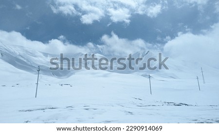 Mountains and hills covered with snow under the sun and bright blue sky in Gudauri, Georgia