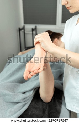 Rehabilitation Specialist, Physical Therapist Makes Foot Massage To Child With Cerebral Palsy, Scoliosis. Health Specialist, Rehabilitation. Vertical plane. High quality photo