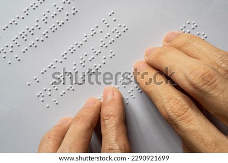 Blind person reading book. The Braille letters in a paragraph are A to Z and 1 to 0 in alphabetical order.