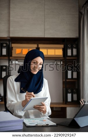 Young Arabic female entrepreneur wearing a hijab working online with a laptop at modern office
