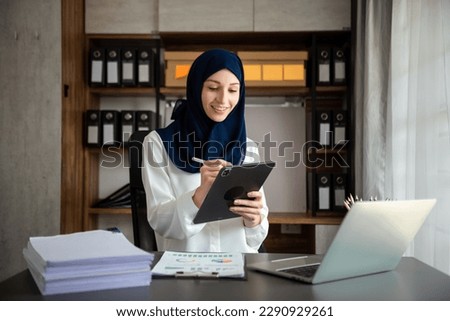 Young Arabic female entrepreneur wearing a hijab working online with a laptop at modern office
