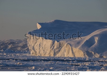Huge iceberg at soft light of sunset with blue sky