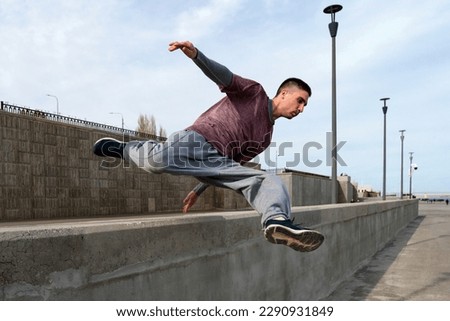 Sports man doing parkour. Parkour athlete training in city in sportive clothes. Free runner jumping have workout at daytime. Royalty-Free Stock Photo #2290931849