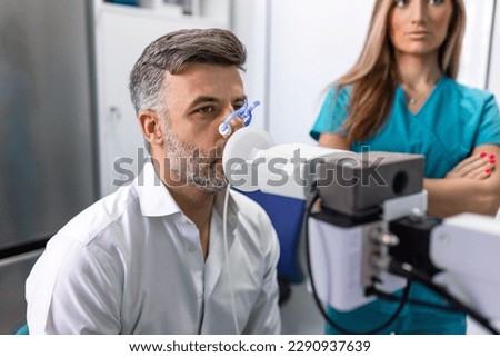 Man performing pulmonary function test and spirometry using spirometer at medical clinic. Spirometry of lungs Royalty-Free Stock Photo #2290937639
