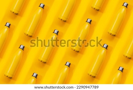 Seamless pattern made with steel thermo water bottles of yellow color on yellow background.
