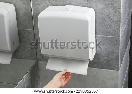 Woman taking new fresh paper towel from dispenser in bathroom, closeup Royalty-Free Stock Photo #2290952557