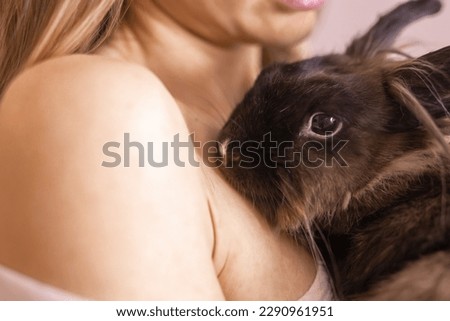 Close-up girl with adorable rabbit indoors, close up. Lovely pet and animal concept