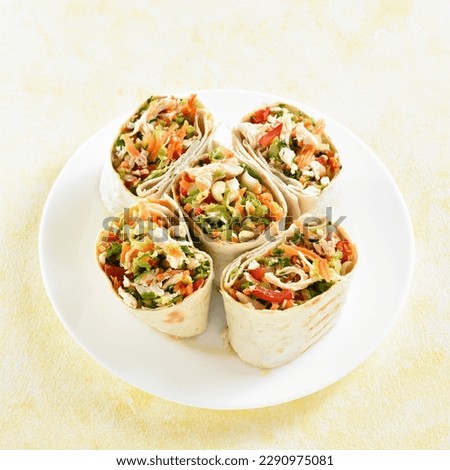 Tortilla wraps with chicken and fresh vegetables on plate over light background. Close up view