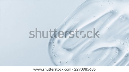 Serum gel smear on blue background. Cosmetic transparent gel serum texture. Royalty-Free Stock Photo #2290985635