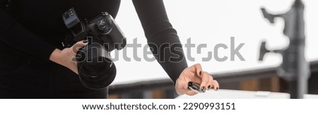 partial view of african american content producer holding mascara and professional digital camera in photo studio, banner