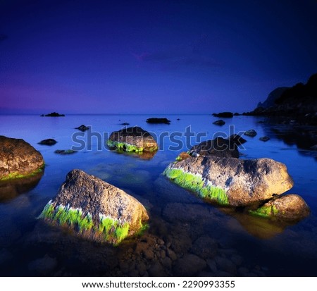 Large stones covered with algae are illuminated by a lantern in the dark sea. Location place of Crimea peninsula, Ukraine, Europe. Photo wallpaper. Art photography. Discover the beauty of earth.