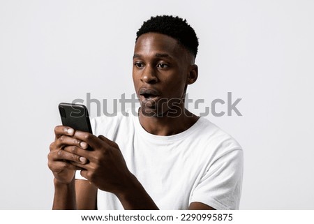 Portrait close up shot of african american black guy holding new modern laste series cellphone smartphone in hands observing photos receiving bad news emotional guy stunned terrified.