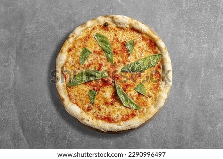 Pizza Margherita from sourdough dough with tomato sauce, mozzarella cheese and basil leaves. Pizza lies on a gray stone background.