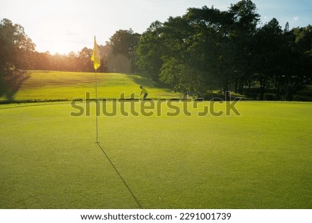 Blurred Golfer putting ball on the green golf, lens flare on sun set evening time.