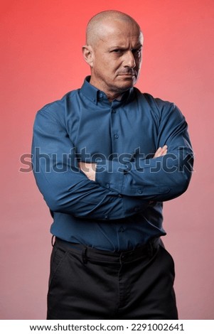 Distrustful businessman with arms folded over roman color background, isolated Royalty-Free Stock Photo #2291002641