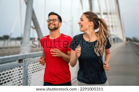 Early morning workout. Happy couple running across the bridge. Living healthy lifestyle. Royalty-Free Stock Photo #2291005311