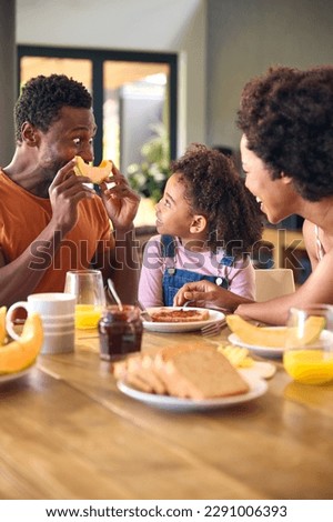 Family Shot With Parents And Daughter At Home Making Funny Faces With Melon Before Eating Breakfast Royalty-Free Stock Photo #2291006393