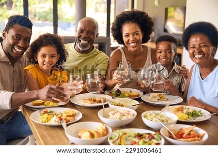 Multi-Generation Family Around Table Doing Cheers With Water Before Serving Food For Meal At Home Royalty-Free Stock Photo #2291006461