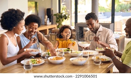 Multi-Generation Family Sitting Around Table Serving Food For Meal At Home Royalty-Free Stock Photo #2291006501