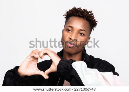 Cute adorable stylish man guy with adorable hairdress showing kisses at camera holding hands in heart shape.