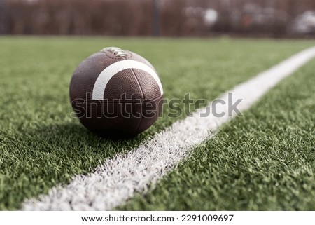 American football ball on green grass field background. Royalty-Free Stock Photo #2291009697