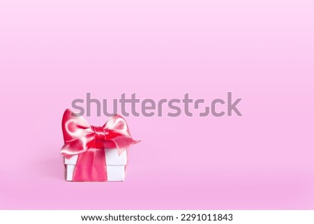 Mock-up poster, gentle white gift box with pink bow on light pink background. Holiday concept. present festive for the holidays. Mother's Day, Birthday, Wedding, Christmas. Copy space