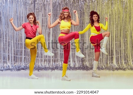 Beautiful young women in pink and yellow sportswear, bodysuits and leggings training, doing aerobics exercises. Active lifestyle. Concept of retro fitness, sport, 80s fashion, beauty, health