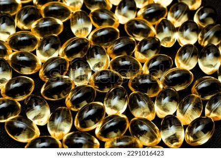 Macro Close up of Omega 3 gel capsule on a reflective black background.