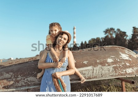 happy little girl of 5 years hugging mother in yellow and blue dresses on beach